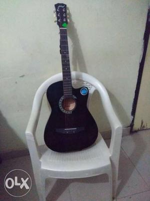 Black Acoustic Guitar On White Armchair
