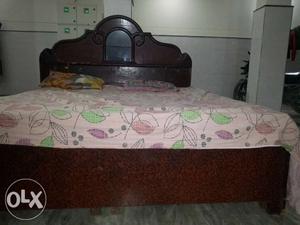 Brown Wooden Bed Frame With White And Green Floral Bedspread
