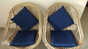 Two cane chairs with cushions.