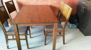 A 4 chair dining table with wooden finish