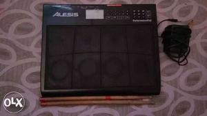 Black Alesis Drum Machine With Pair Of Drumsticks