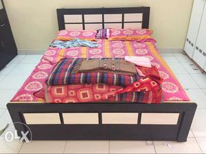Black Wooden Bed And Multicolored Floral Bed Sheet
