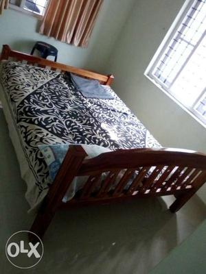 Brown Wooden Bed Frame With White And Black Floral Bedspread