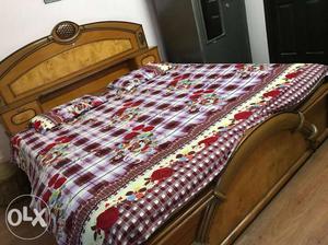 Brown Wooden Bed And Red, White, And Green Floral Bedspread