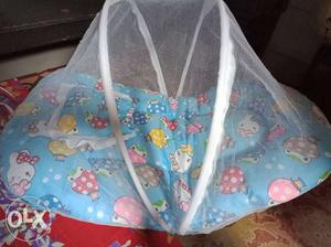 Blue Net covered bed for infant baby with pillow